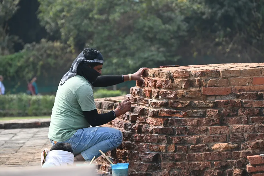 Mason raking out and repointing the mortar joints on an older brick wall