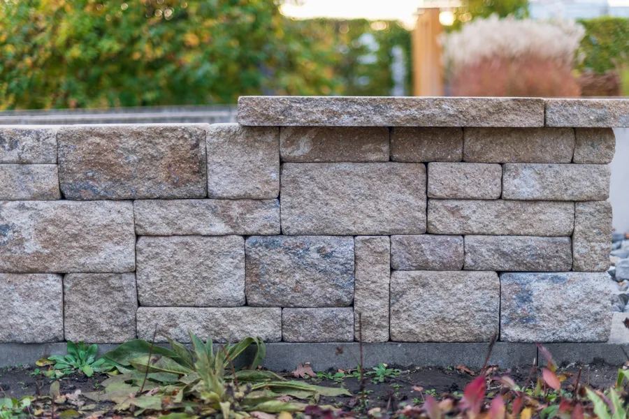Capped natural stone garden wall in front of a planted bed