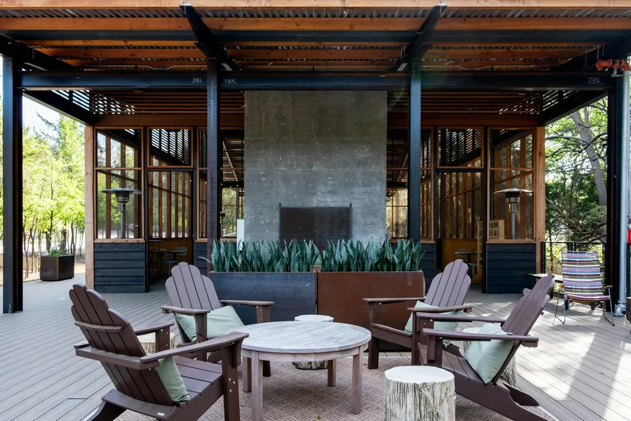 Covered outdoor living area with a tall stone fireplace and seating